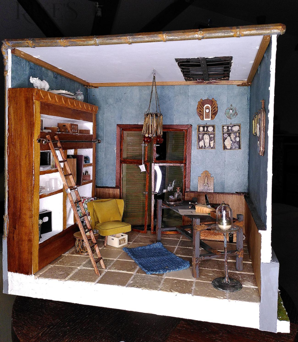 IMG_20201228_013733 Miniatur eines Studios eines Bildhauers für Zähne, im Raum sind ein wandgroßes Regal, eine Doppeltür nach draußen mit Sonnenblenden davor, einem großen Arbeitstisch, einem stylischen senfgelben Samtsessel, einem blauen Teppich, einem Oberlicht und verschiedenen Dekoartikeln mit Zähnen