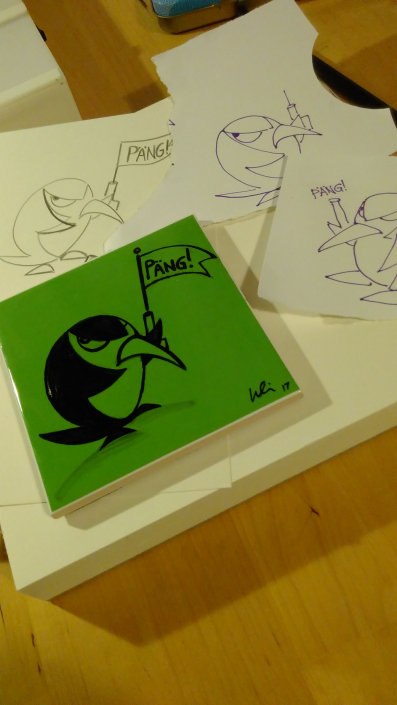Grüne Fliese mit schwarzer Fineliner-Zeichung eines Pinguins, der eine abgefeuerte Startpistole hochhält