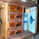Detailansichten eines Schaukastens mit Elementen aus Holz, Glas, Metall und Miniaturen aus dem Alltag. Neben Holzfarben ist die dominierende Farbe ein helles Blau.