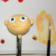 Modellierter Kopf einer Kinderfigur, der auf einem Bleistift steckt und gerade farbig bemalt wird
