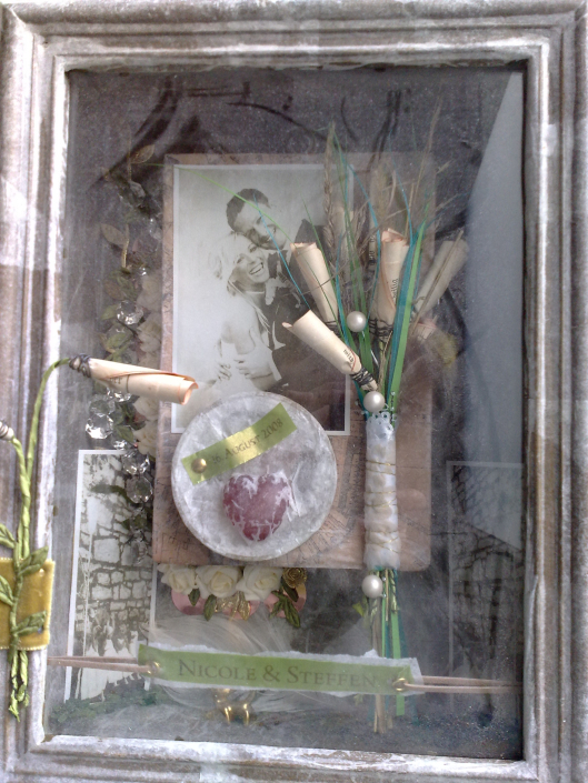 Hochzeitskasten zu einer Hochzeit im Jahr 2018 mit einem Foto des Brautpaares, dem Brautstrauß, Perlen, Blüten und Bändern