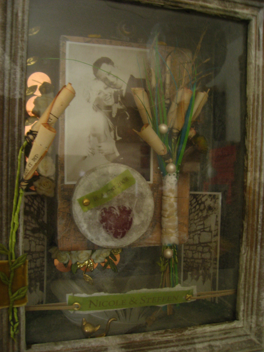 Hochzeitskasten zu einer Hochzeit im Jahr 2018 mit einem Foto des Brautpaares, dem Brautstrauß, Perlen, Blüten und Bändern