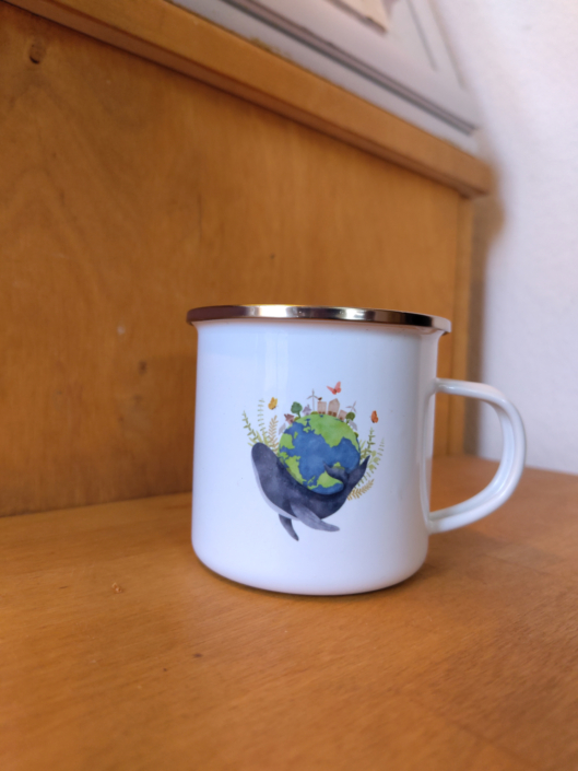 Emailletasse mit einer Illustration von einem Wal, der die Welt trägt