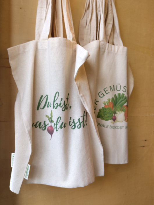 Mehrere Einkaufsbeutel, auf dem vorderen ist der Spruch "Du bist was du isst" mit Radieschen zu sehen
