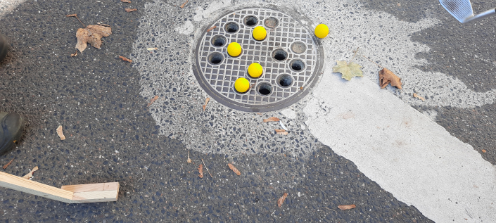 Gullideckel mit einigen gelben Golfbällen und einem Schläger aus Holz