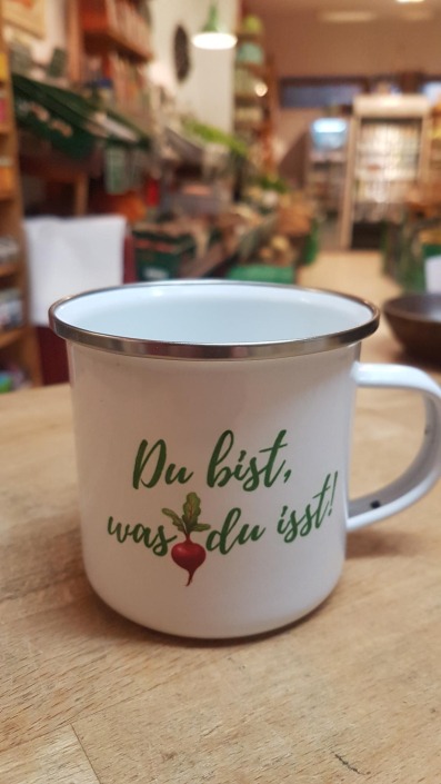 Tasse aus weißen Emaille bedruckt mit dem Satz "Du bist was du isst" und einem Radieschen